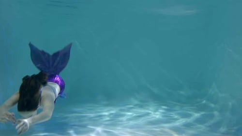Charmante Frau im Meerjungfrauenkostüm schwimmt anmutig unter Wasser