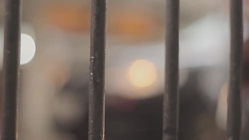 View of a window from inside an old prison cell in a cold and busy city with cars passing on the out