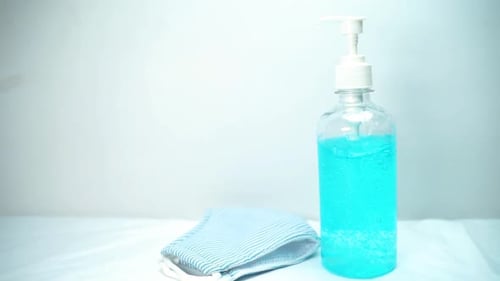 Close up face mask and a bottle of blue hand gel sanitize. Slow movement shot
