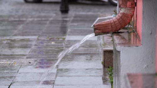 Water Flows from Gutter on Wet Sidewalk