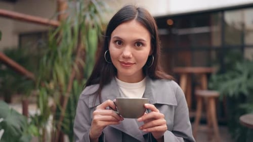 Cheerful Young Woman Enjoying Coffee in a Cozy Cafe