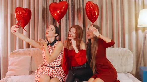 Three Close Girlfriends Making Selfies with Heartshaped Balloons on Smartphone Celebrating Their