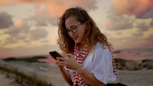 Young European Women Girl By the Sea Takes a Selfie and Photographs the Sunset