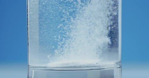 Aspirin Tablet Falls Starts to Bubble Macro Plan Slow Motion Blue Background