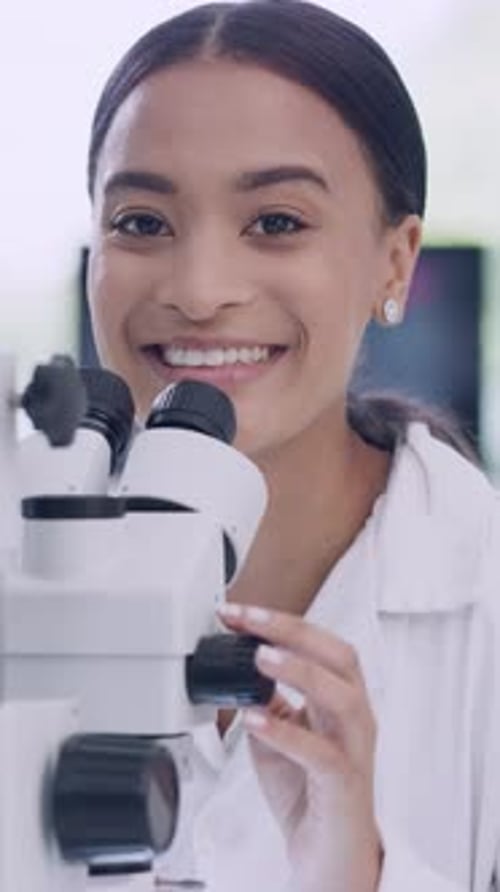 Smiling Woman Uses Microscope in Bright Lab