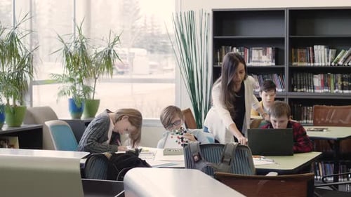 Professeur du premier cycle du secondaire et étudiants étudiant à la table de la bibliothèque, garçons