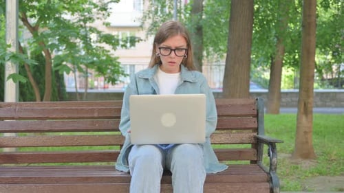 Perplexed Woman Using Laptop on Park Bench