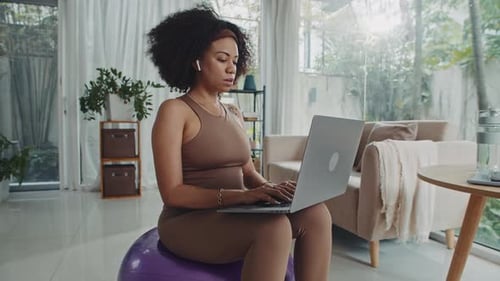 Woman Works on Laptop Sitting on Exercise Ball