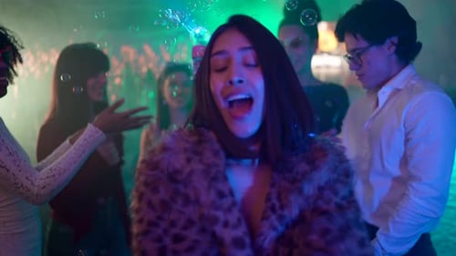 Joyful young woman dancing with friends at nightclub party
