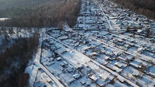 Enjoy Breathtaking Aerial Shots of a Snowcovered Village in a Winter Wonderland with a Defocused