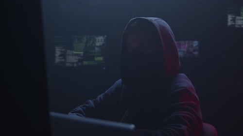 Un misterioso hacker que trabaja en una habitación con poca luz llena de sombras y código