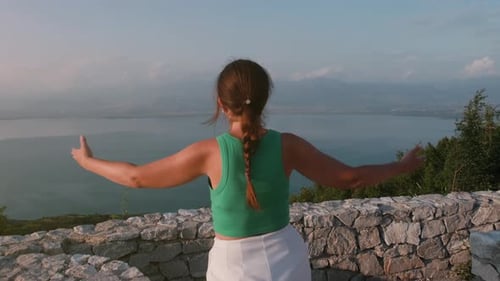 View from the back: a girl walks up to the observation deck at the top of a mountain.