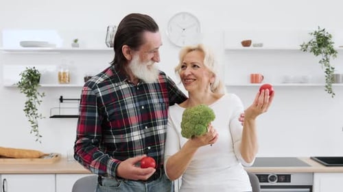 Senior Couple Holds Vegetables in Kitchen