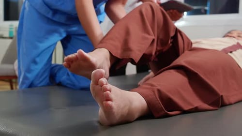 Nurse physiotherapy with elderly patient while stretch leg in hospital.