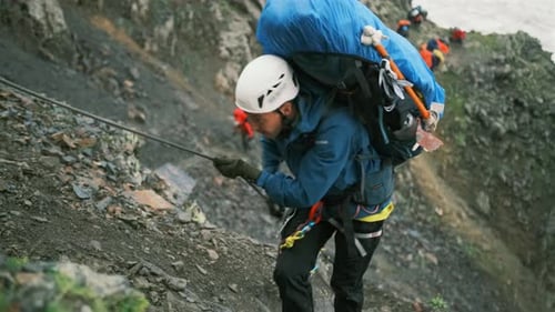 The climber climbs up the mountain with a backpack with equipment