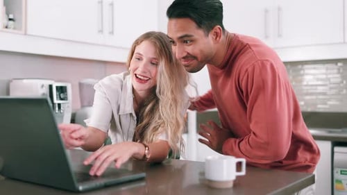Laughing Couple Sharing Laptop in Bright Modern Kitchen