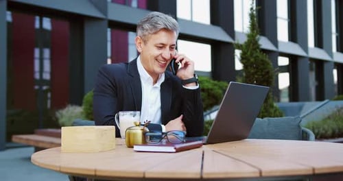 Man Talking on Phone While Working on Laptop