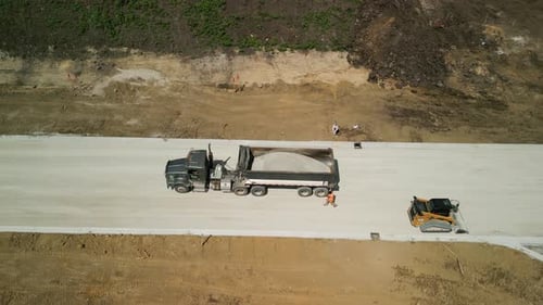 Construction Truck Tipping Dumping Gravel on Road Construction Site Aerial Top Footage