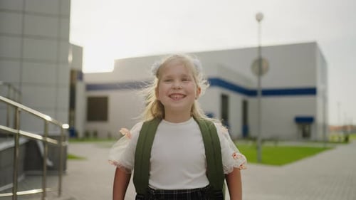 Colegiala sonriente de 7 años mirando un retrato a la cámara en el patio trasero de la escuela en un día soleado