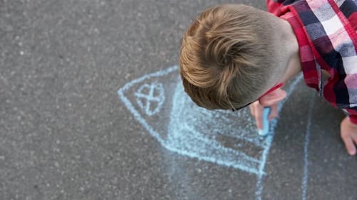 Child draws dream house on asphalt with chalk. Real estate purchase concept.