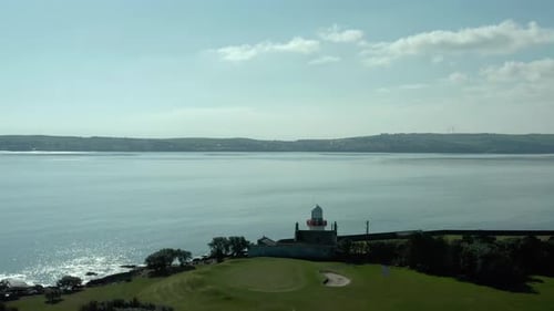 Aerial birds eye view flying over lighthouse at sea coast at day
