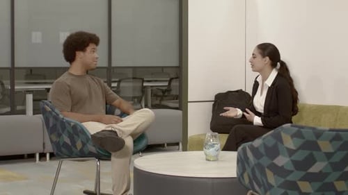 African American male in his 20's in an office setting talking to an Arab American female in her 20'