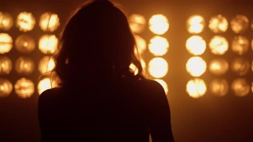 Silhouette einer professionellen Sängerin, die in Nachtclub-Lichtern aus nächster Nähe auftritt