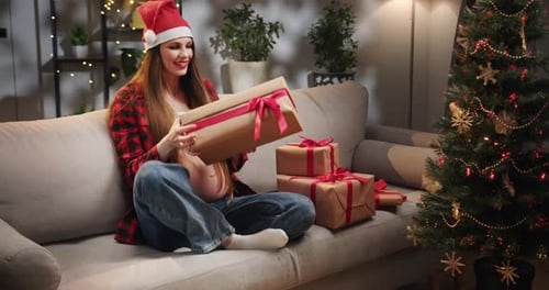 Woman on Couch Opens Christmas Present
