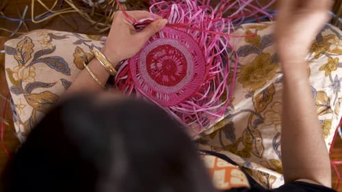 Overhead View Of An Indigenous Woman Hand Weaving A Colorful Basket.