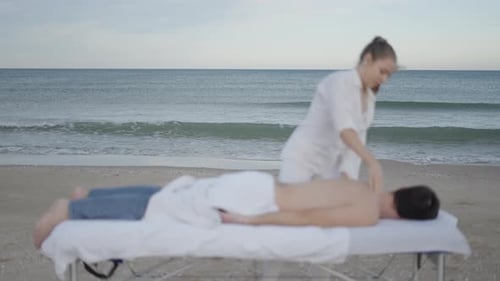 Sea Waves in the Background and Woman Performing Massage on the Foreground Unfocused