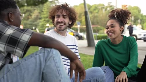Jovens amigos sentados na grama conversando e compartilhando bons momentos felizes