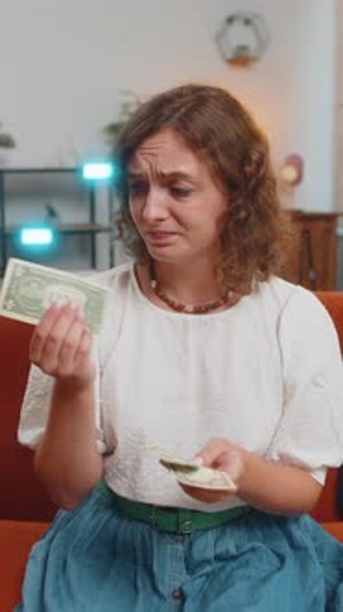 Upset Young Woman Sitting on Sofa Counting Money Having Not Enough Worried About Finances Debts