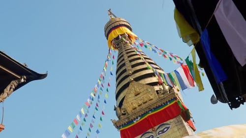 View of Swayambhunath pagoda roof, an ancient buddhist shrine with prayer flags moving in the wind,