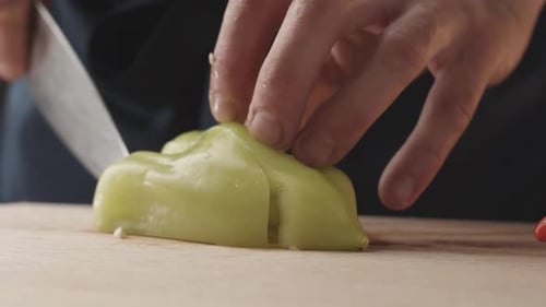 Front View of the Young Chef Cut Thin Slices of a Piece of Green Pepper