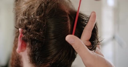 Hombre de cerca cortándose el pelo con tijeras obteniendo los servicios de un peluquero