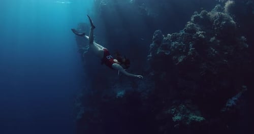 Female Freediver Dive and Swims Undersea in Deep Ocean with Sun Rays Free Diving in Blue Sea Near