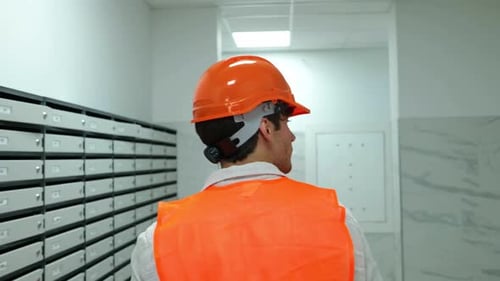 Male Construction Worker in Helmet and Waistcoat Walking in the Building Indoor on the Construction