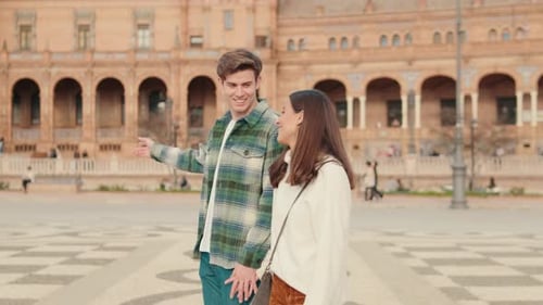 Happy young couple man and woman walking in the square of an old European city