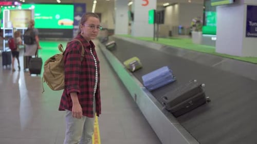 Female tourist with backpack is waiting her luggage in airport