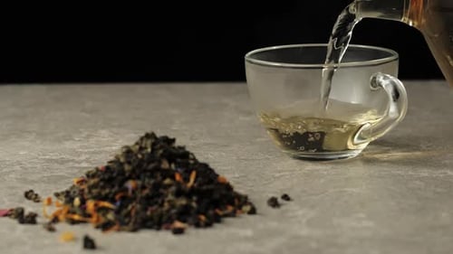 Tea ceremony. Green tea is poured into a transparent mug with on table against black