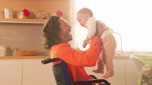 Man in Wheelchair Holds Baby in Bright Kitchen