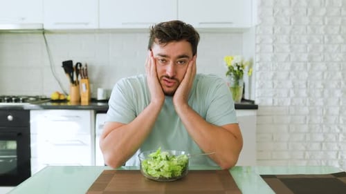 Man Looks Unhappy With Salad in Kitchen