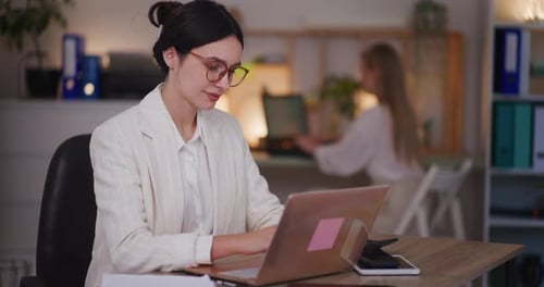 Deux femmes travaillent au bureau jusqu'au soir