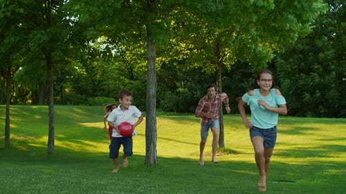 Front View of Children with Parents Running in Summer Park. Joyful Family
