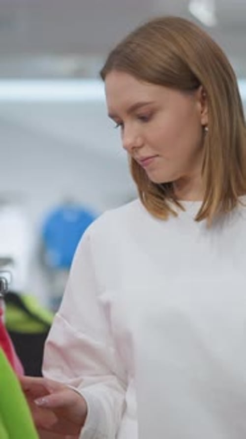 Woman Browsing Colorful Clothing Rack in Retail Store