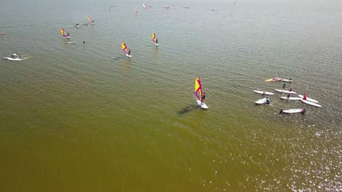 Vue épique prise par Drone d'un véliplanchiste débutant. La caméra s'éloigne, révélant l'immensité du lac et
une multitude