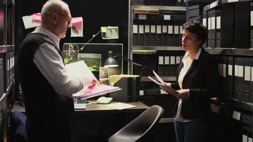 Colleagues Reviewing Files in Dim Office