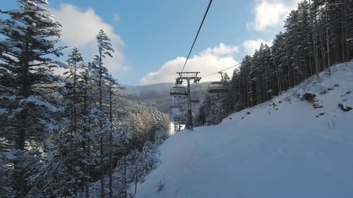 Riding on Ski Lift Between Snow Covered Pinetrees in the Morning POV Shot Winter Vacation Concept