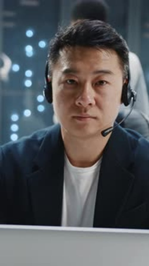 Man in Headset in Data Center Looks Confidently