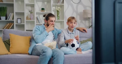 Man and Child Enjoying Soccer Match on Television